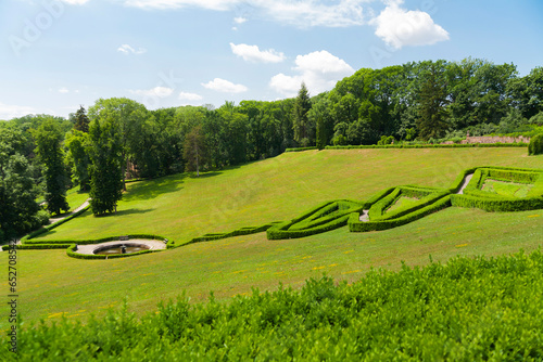 View of the park (botanical garden) Sofiyivka in summer. Green grass and blue sky, geometric composition of green bushes on a hillside photo