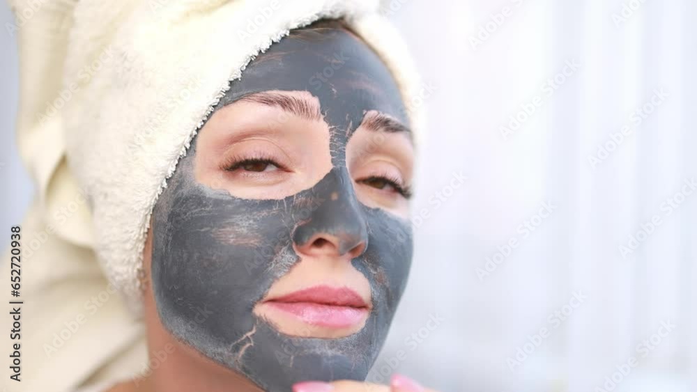 A woman applies a cleansing mask to her face. A woman applies a cleansing mask to her face.