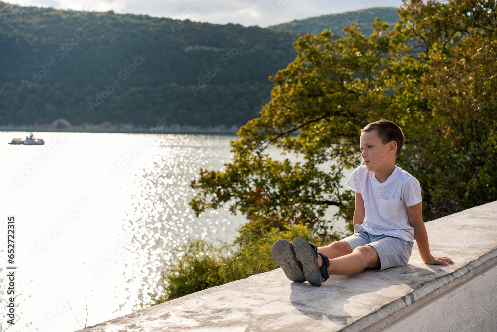 pensive boy admiring the view of the lake, travel and active lifestyle 