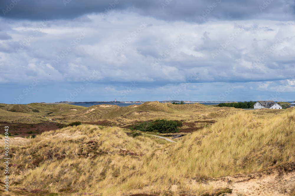 Dramatische Wolken im Dünenbereich der Nordseeinsel Amrum der Blick geht hinüber zur Nachbarinsel Sylt mit dem Leuchtturm von Hörnum