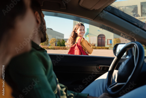 Canvas-taulu Mother and father dropping off daughter in front of school, girl turning back to