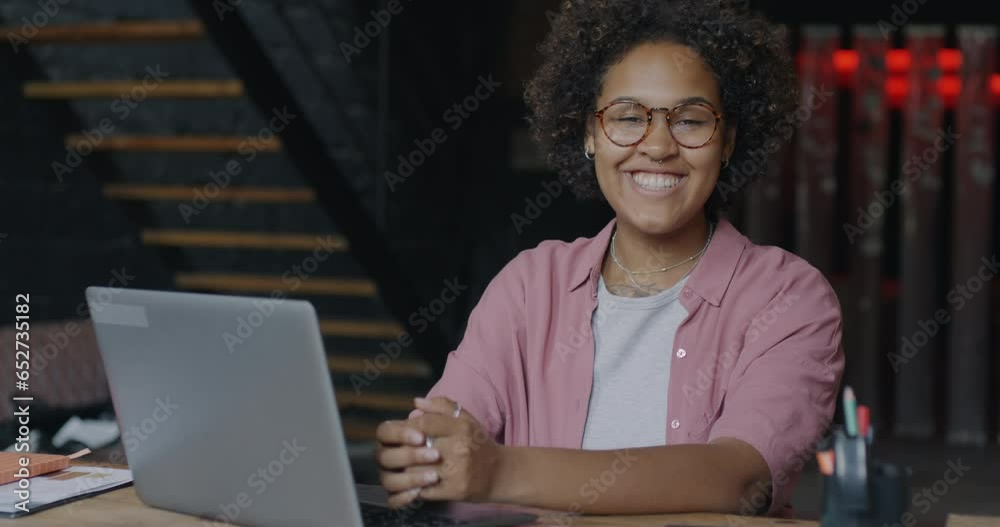 Portrait of ambitious African American businesswoman working with laptop then turning to camera and smiling in office. People and career concept. Portrait of ambitious African American businesswoman working with laptop then turning to camera and smiling in office. People and career concept.