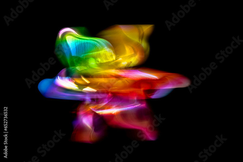 A front view of a regular toy pinwheel windmills with six differently psychedelic colored vanes rotating on a stick on a black screen background, slow shutter speed motion blur