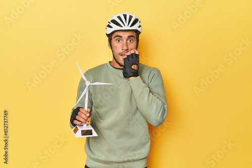 Cyclist with windmill, clean transport theme biting fingernails, nervous and very anxious. © Asier