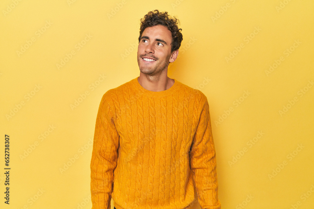 Young Latino man posing on yellow background relaxed and happy laughing, neck stretched showing teeth. Young Latino man posing on yellow background relaxed and happy laughing, neck stretched showing teeth.