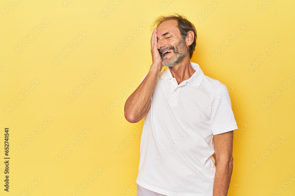 Caucasian middle-aged man in yellow studio laughing happy, carefree, natural emotion. Caucasian middle-aged man in yellow studio laughing happy, carefree, natural emotion.