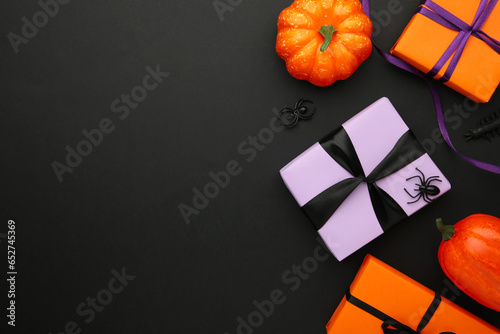 Happy Halloween holiday concept. Flat lay gift boxes, orange pumpkins, bats, spiders on black background. Halloween greeting card template.