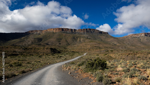 A dirt road in Karoo National Park with white clouds.