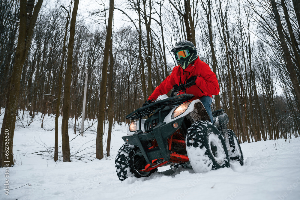 Snow, trees, adventure. Man is riding ATV outdoors in the winter forest Snow, trees, adventure. Man is riding ATV outdoors in the winter forest