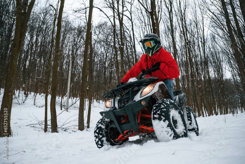 Snow, trees, adventure. Man is riding ATV outdoors in the winter forest