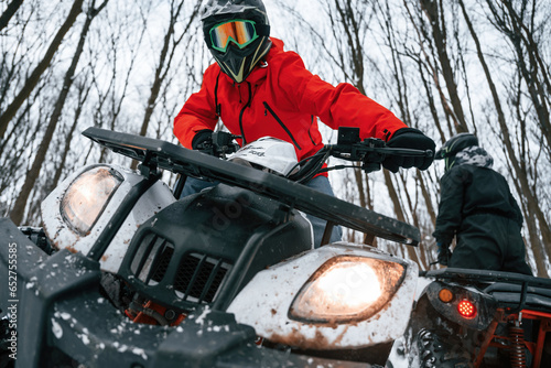 Two people are riding ATV in the winter forest photo