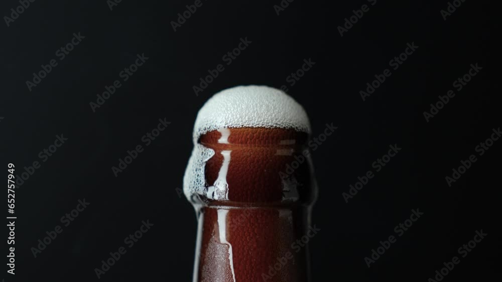 Hand putting beer bottle with froth, close-up