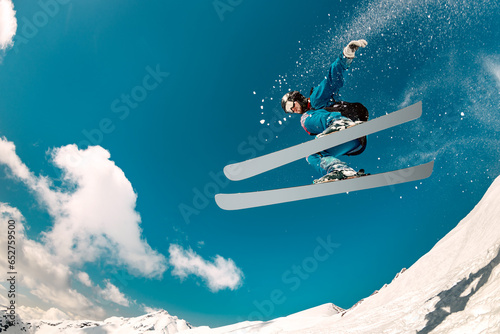 Fast young skier jumps and fly in cloud of powder snow. Winter sports at ski resort photo