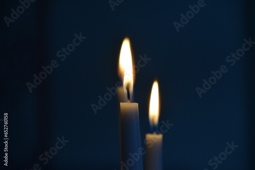 Closeup shot of two lit candles slowly burning in a dark room
