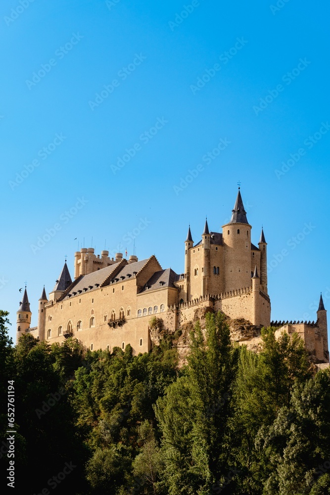 Historic Alcazar Castle surrounded by green trees in Segovia, Spain