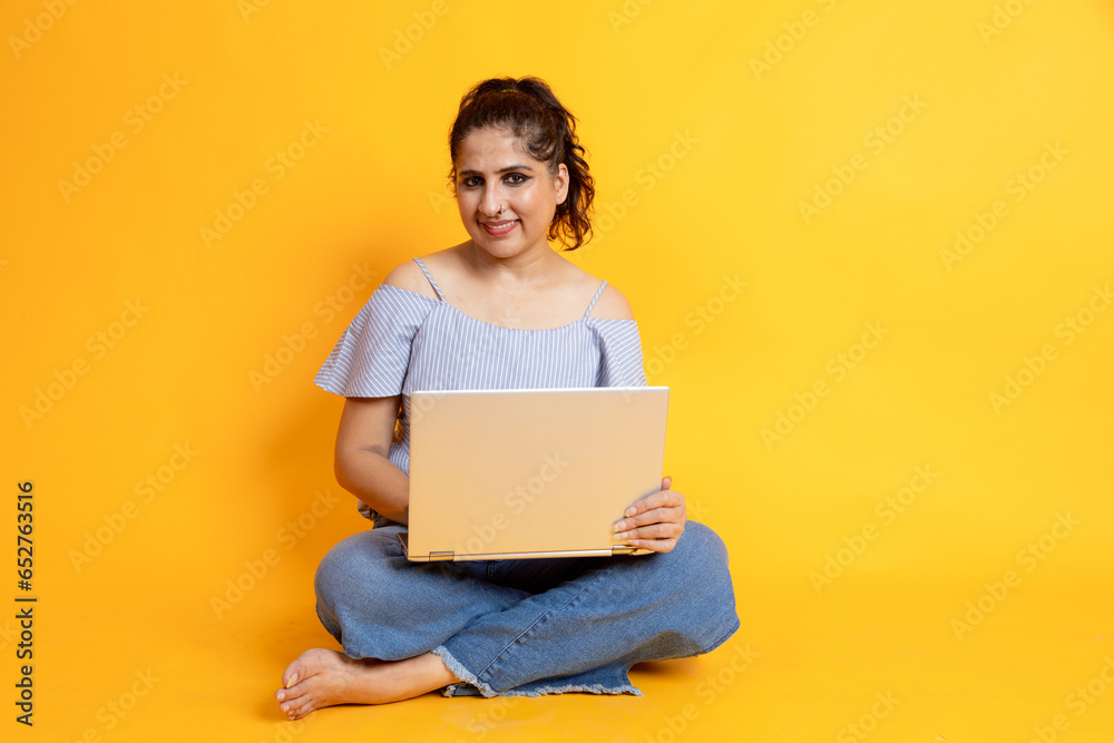 young woman sitting isolated over yellow background using laptop computer. Looking camera young woman sitting isolated over yellow background using laptop computer. Looking camera