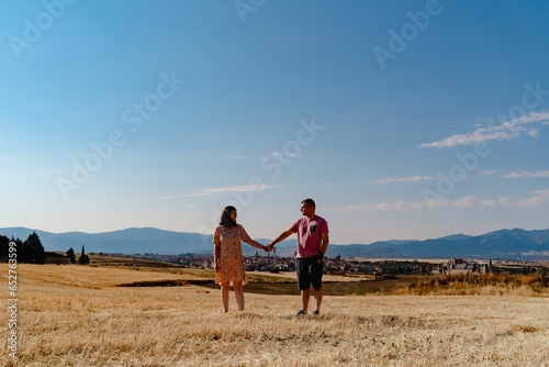 Lovely couple holding hands walking through a yellow dry meadow in Spain