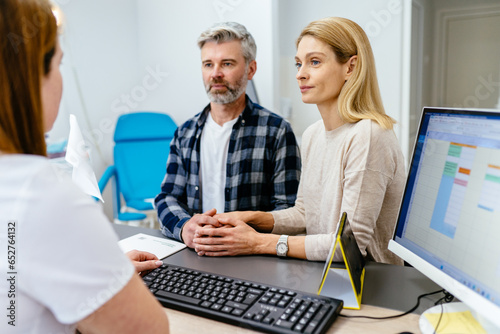 Worried mature couple talking to a doctor in the office. Middle age man and woman at a gynecologist consultation appointment in clinic. Family, wellness and infertility consultation concept