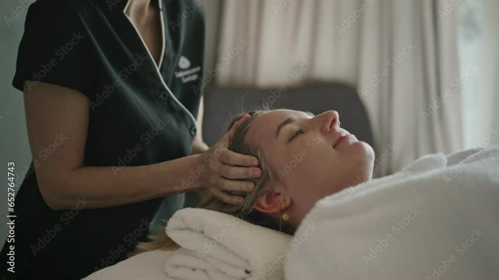 Young woman receiving relaxing head massage lying down in natural light Young woman receiving relaxing head massage lying down in natural light