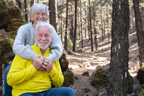Lovely bonding happy senior couple embracing enjoying mountain hike in the forest expressing joy and freedom, retired seniors man and woman and healthy retirement lifestyle concept