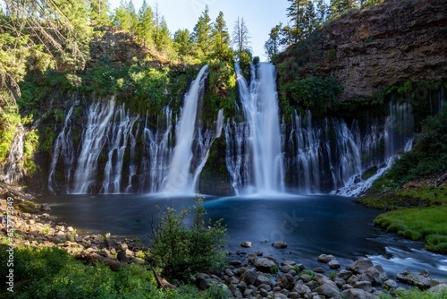 Landscape of Burney Falls surrounded by greenery on a sunny day in California