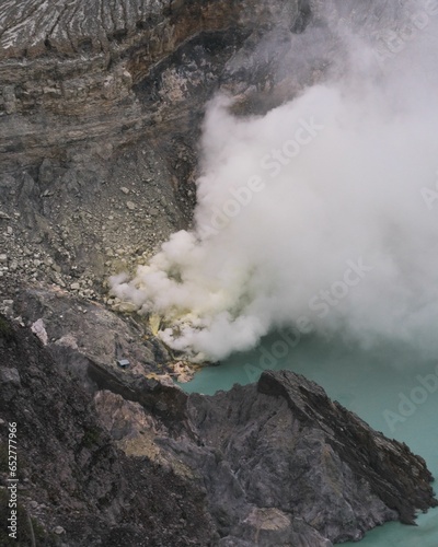 Vertical aerial view of a blue acid lake with sulfur steam near Mount Ijen, Java, Indonesia
