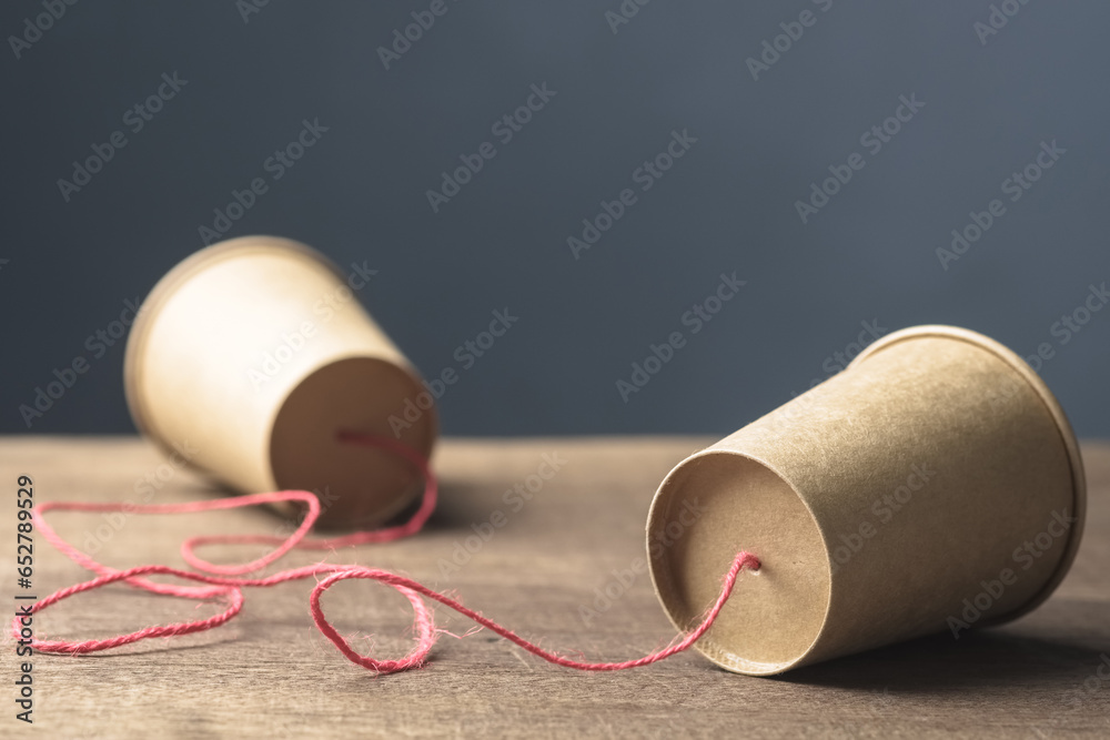 Two brown paper cups with string as old style or toy phone, two way communication - obrazy, fototapety, plakaty 