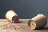 Two brown paper cups with string as old style or toy phone, two way communication