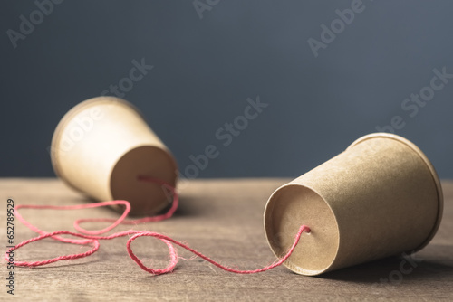 Two brown paper cups with string as old style or toy phone, two way communication photo