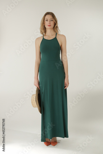 Studio fashion portrait of female model in long tight green jersey dress