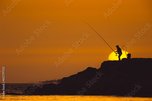A man is fishing at sunset