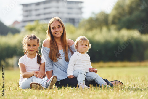Wallpaper Mural Mother with her two little daughters is sitting on the green field Torontodigital.ca