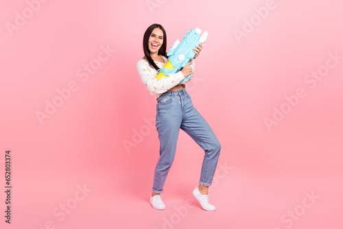 Full length photo of pretty funky lady wear white cardigan shooting water gun isolated pink color background