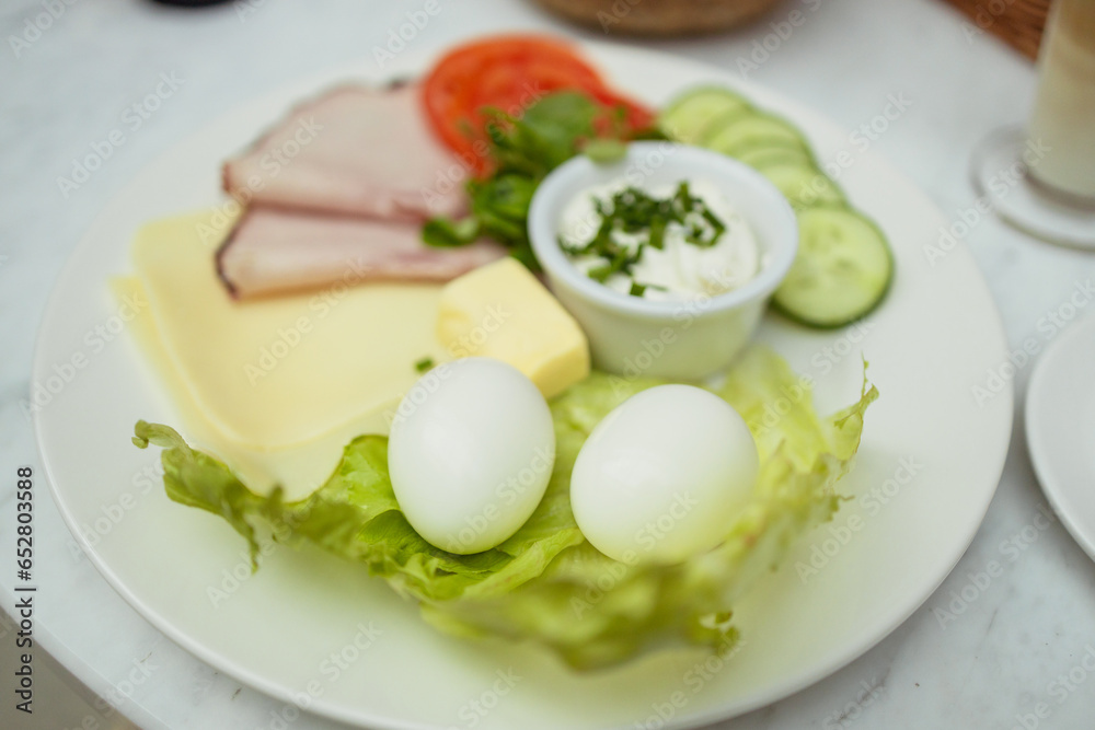 Healthy breakfast with boiled eggs with green salad, cucumber and shank. Latte coffee and fresh cereal bread in the background. Healthy breakfast with boiled eggs with green salad, cucumber and shank. Latte coffee and fresh cereal bread in the background.