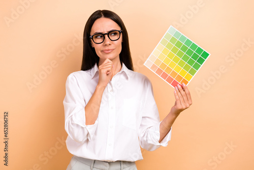 Photo of pensive businesswoman touch chin guess palette card reconstruction renovation her apartments isolated over beige color background