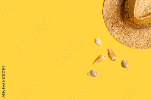 Un sombrero junto a unas caracolas sobre un fondo amarillo liso y aislado. Vista superior y de cerca. Copy space
