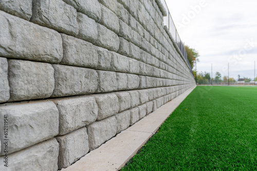 Photos Retaining wall next to a green synthetic turf athletic field.