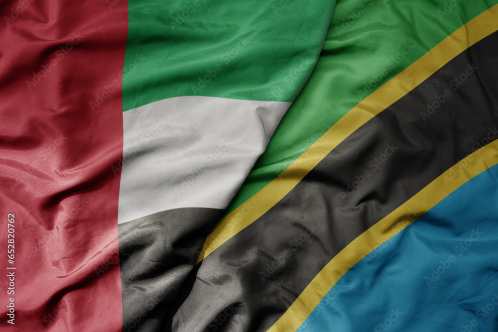 big waving realistic national colorful flag of united arab emirates and national flag of tanzania .