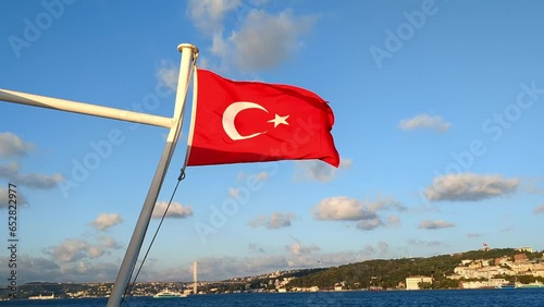 The Turkish flag flutters on a ship against the background of the coast of Istanbul