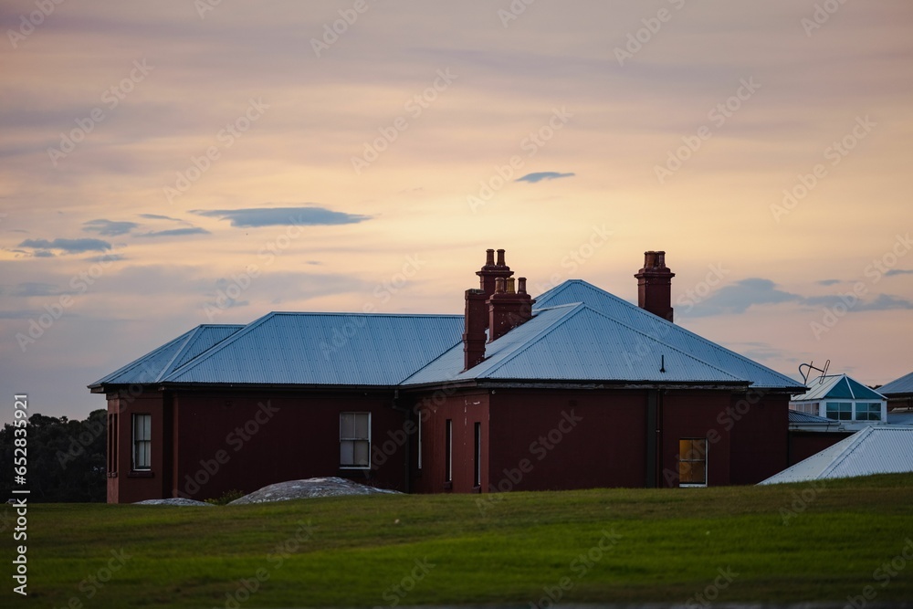 Cozy, rural home basking in the golden sunlight at sunset, in the middle of a lush, green field Cozy, rural home basking in the golden sunlight at sunset, in the middle of a lush, green field