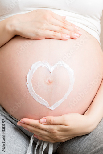 Wallpaper Mural a pregnant girl sits at home on the bed and smears heart an anti-stretch mark cream on her stomach. Pregnancy, motherhood, preparation and expectation concept Torontodigital.ca