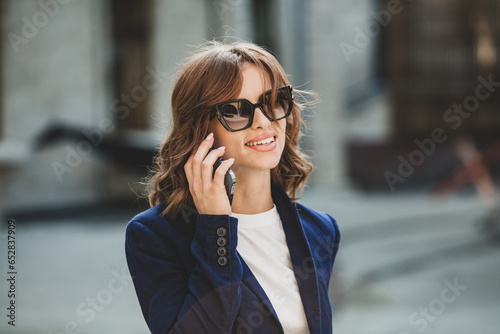 Portrait of a successful business woman in front of modern business building. Young manager poses outside. Woman employee of an office.