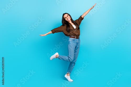 Full size body cadre of girl young flying arms have fun positive playing lightness freedom stylish outfit isolated on blue color background