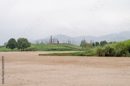 Historical wooden structure in sandy rock ground with green grass and atmospheric mountain backgrounds