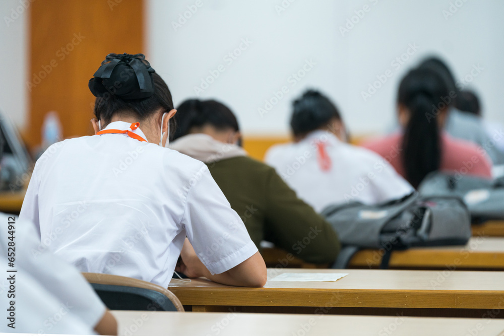 Rear view of university students concentrate on doing examinations via tablet and smartphone in the classroom Rear view of university students concentrate on doing examinations via tablet and smartphone in the classroom