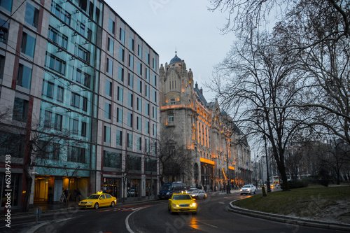 Canvas Print City buildings in the evening with warm street lights and road with taxi cars