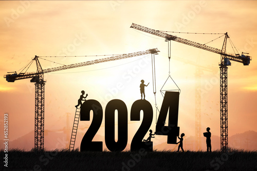 Silhouette engineers working on a construction site To prepare to welcome the new year , cranes and construction teams set the number 2024 in the concept.