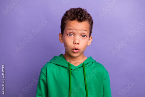 Photo of impressed funky little boy dressed green hoodie big eyes isolated purple color background