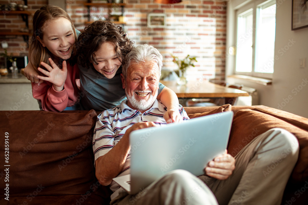 Grandfather video calling with his grandchildren on the couch at home Grandfather video calling with his grandchildren on the couch at home