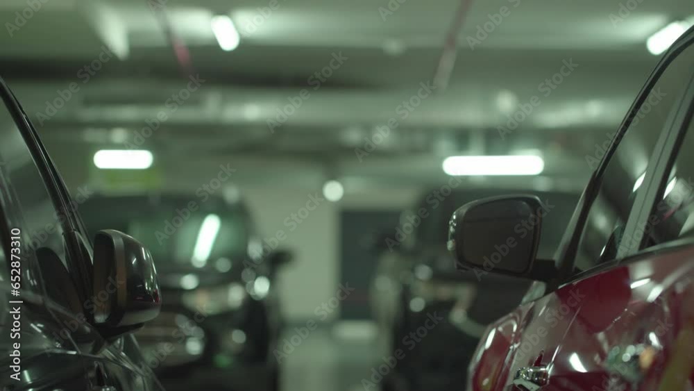 Modern underground parking with unrecognizable moving cars, focusing on the foreground 4K